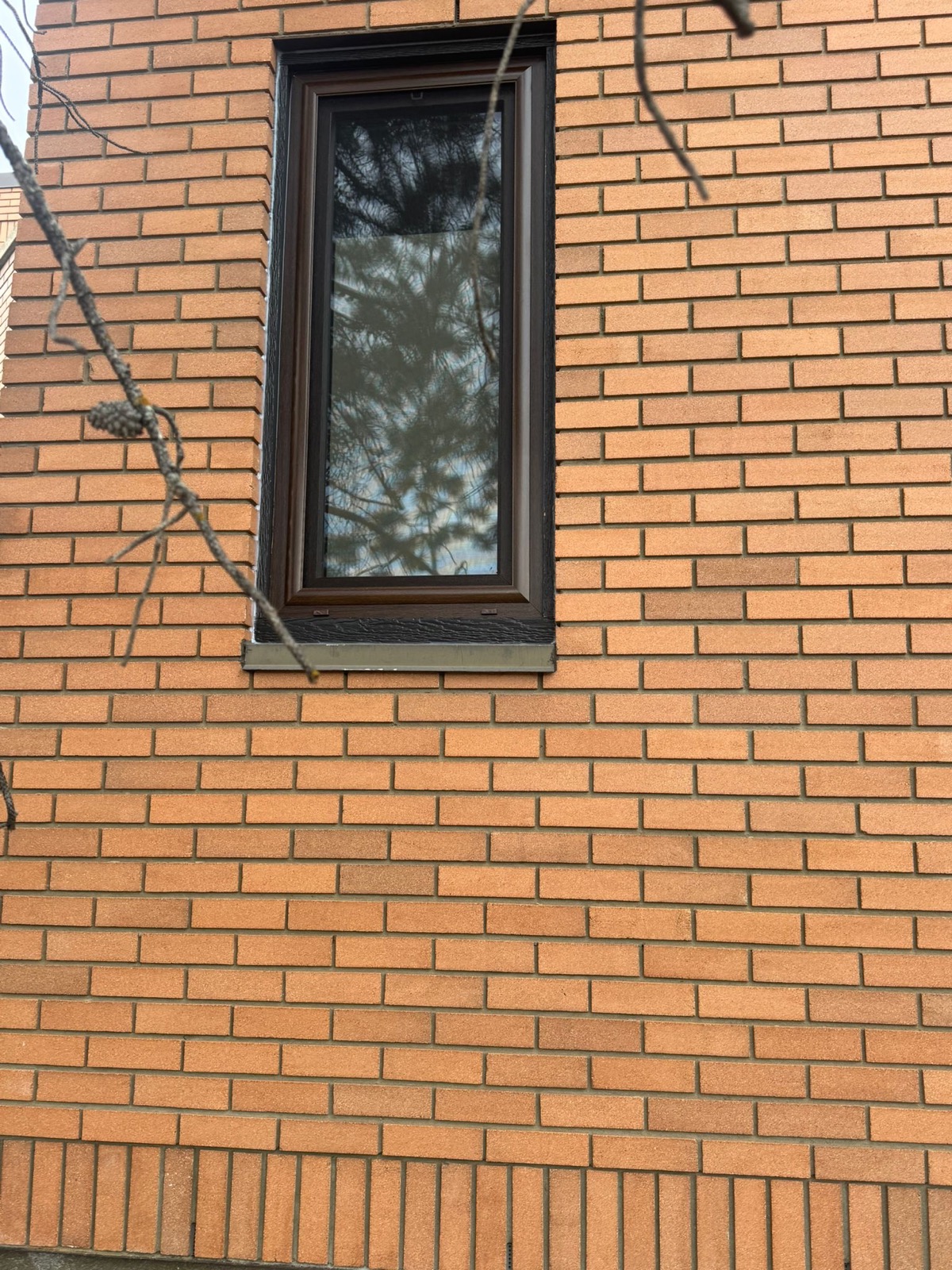 Single tall black-frame casement window on brick commercial wall
