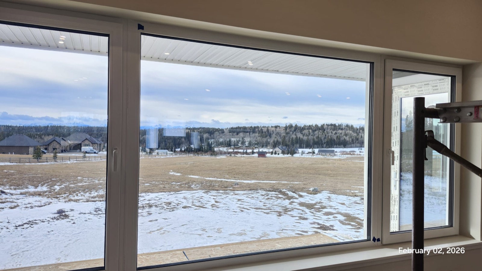 Panoramic picture window interior view of Rocky Mountains from acreage build