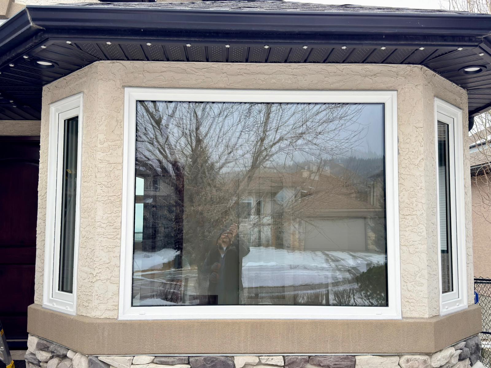 Bay window installation on stucco home with stone base