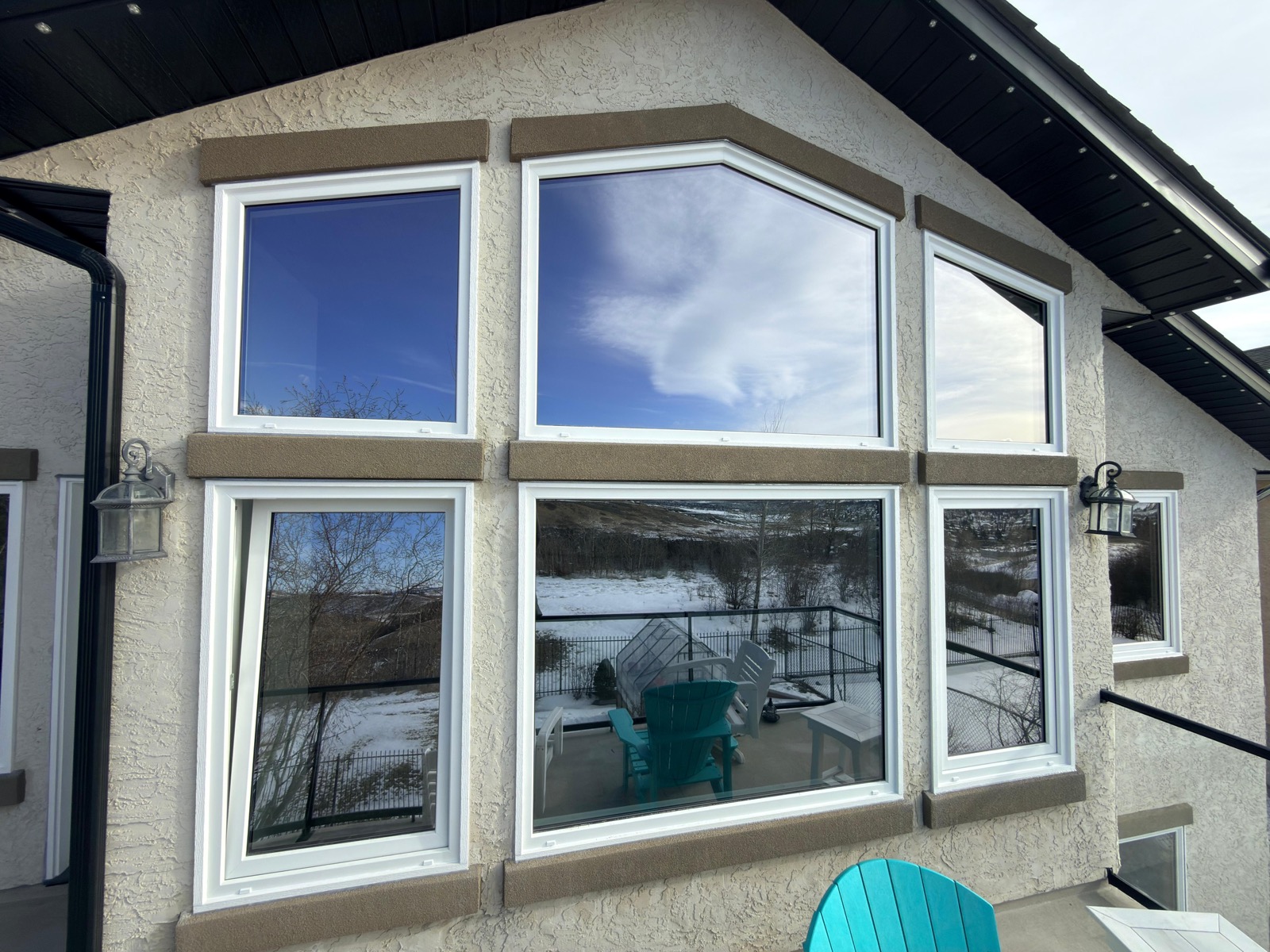 Six-unit cathedral window wall on stucco home overlooking snow-covered hillside