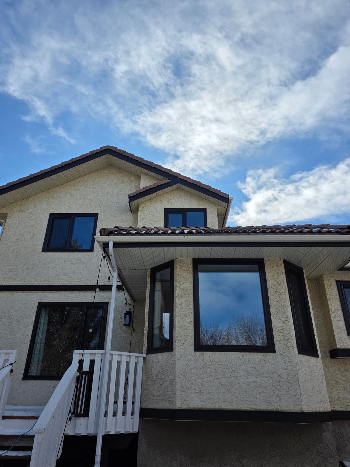 Black-framed picture and casement windows on stucco with Spanish tile