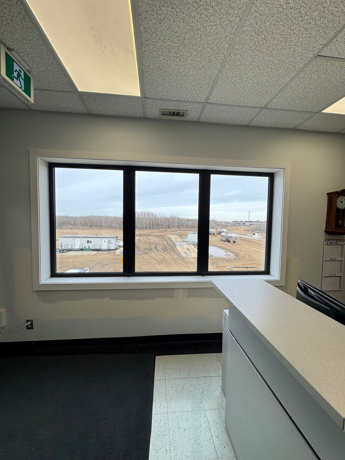 Office interior with triple black-framed window installation, reception and exit signage