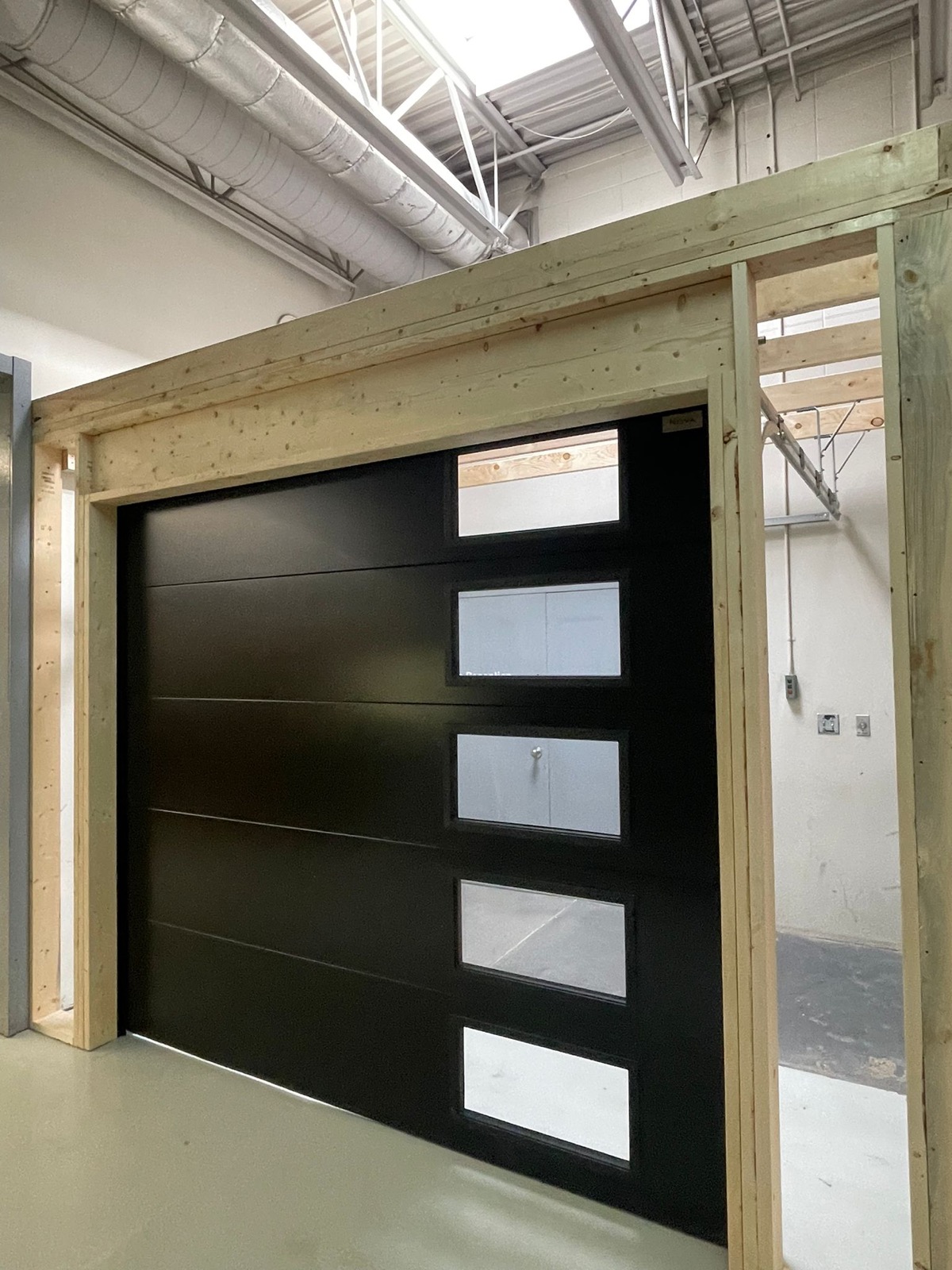Commercial black overhead sectional door with vertical glass strip insert