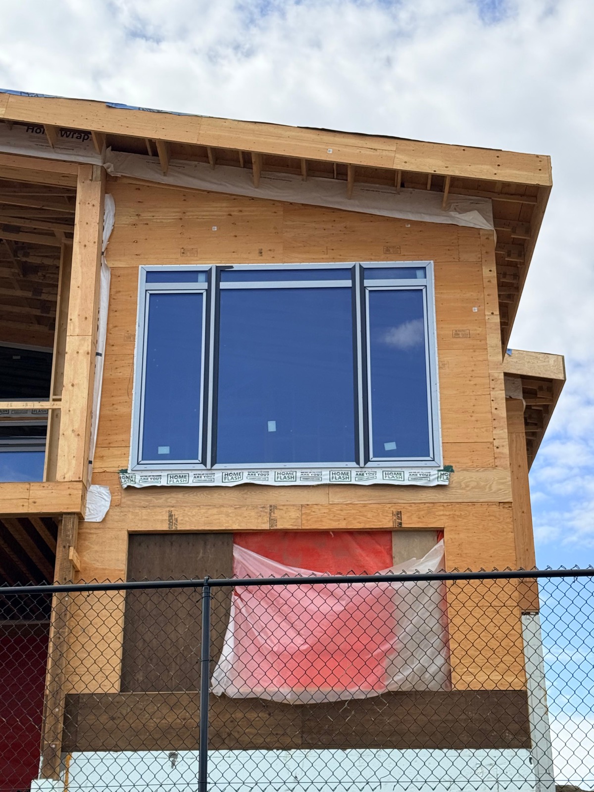 Triple-mullion black-frame window on second-storey Tyvek-wrapped wall