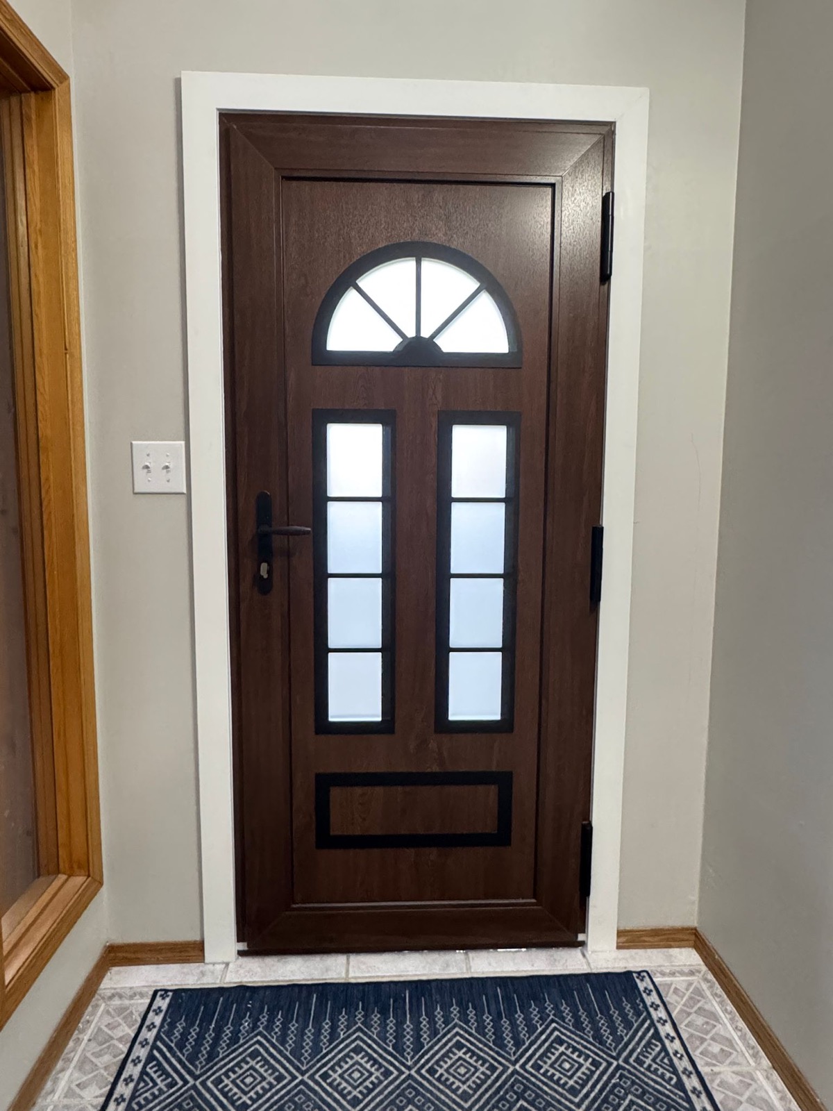 Dark walnut entry door with fan-light and four-pane grid