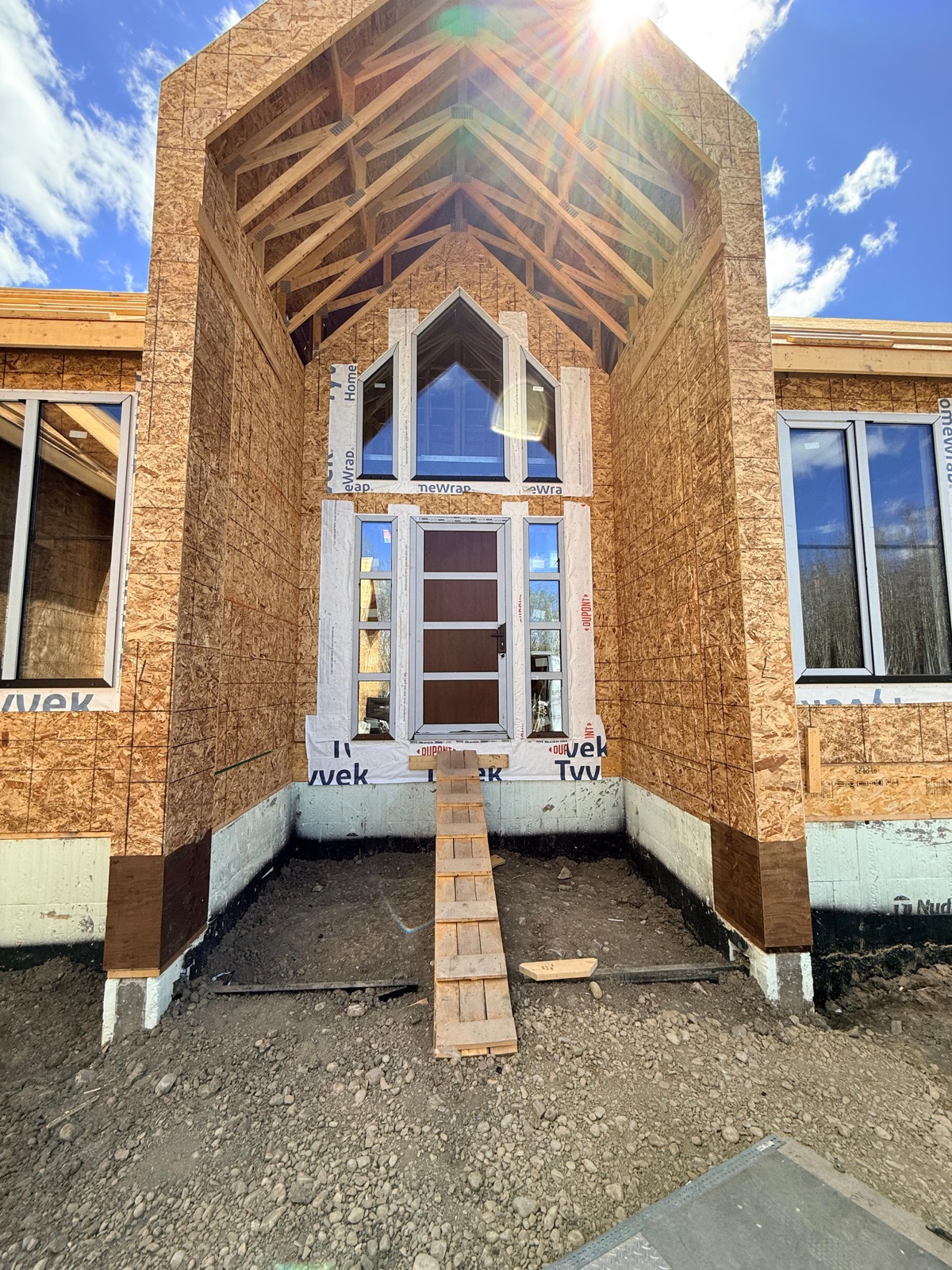 Dramatic vaulted entry porch with arched window over door — OSB-sheathed new build