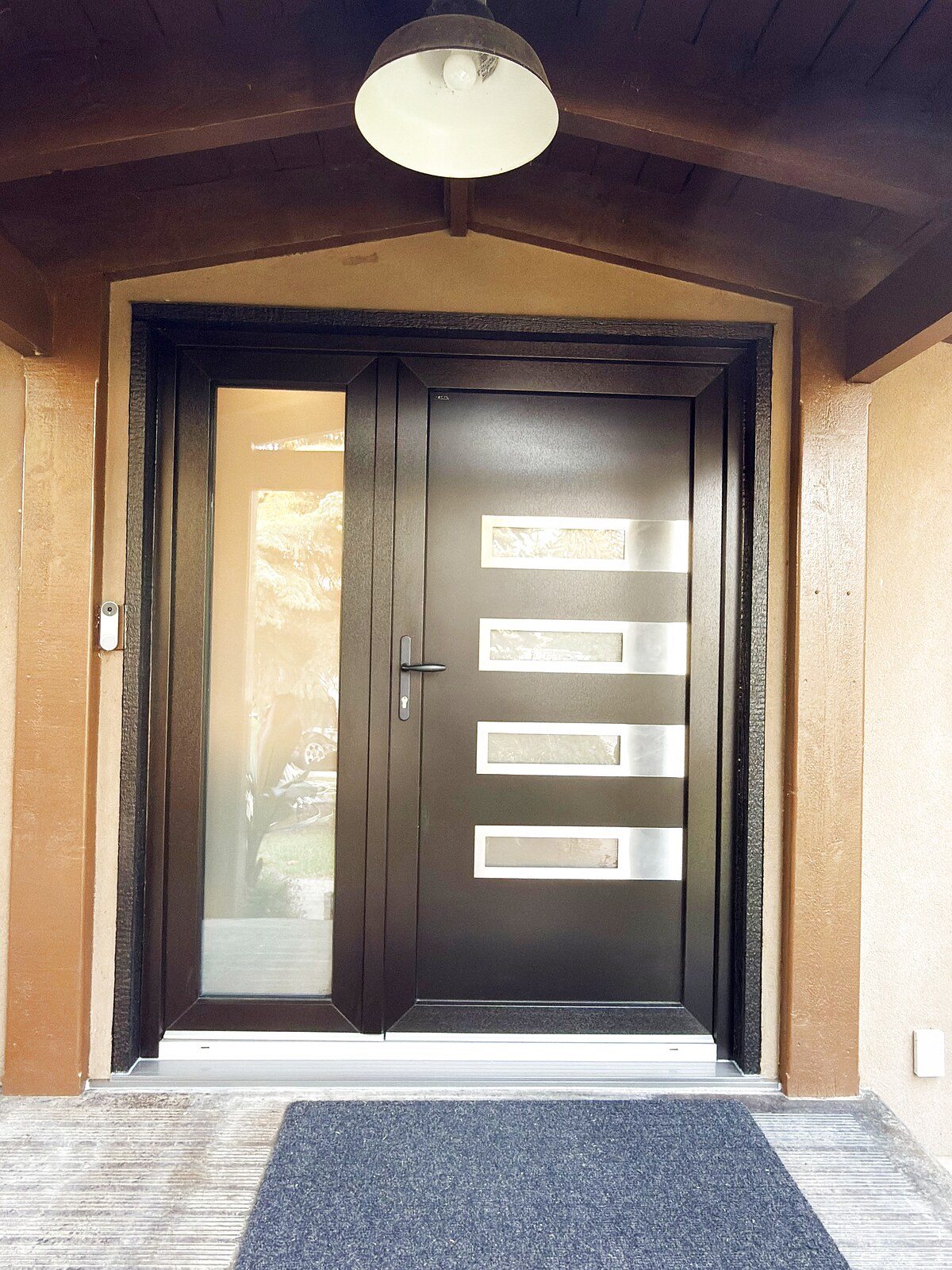 Black modern entry door with four glass slots and a sidelite, covered porch