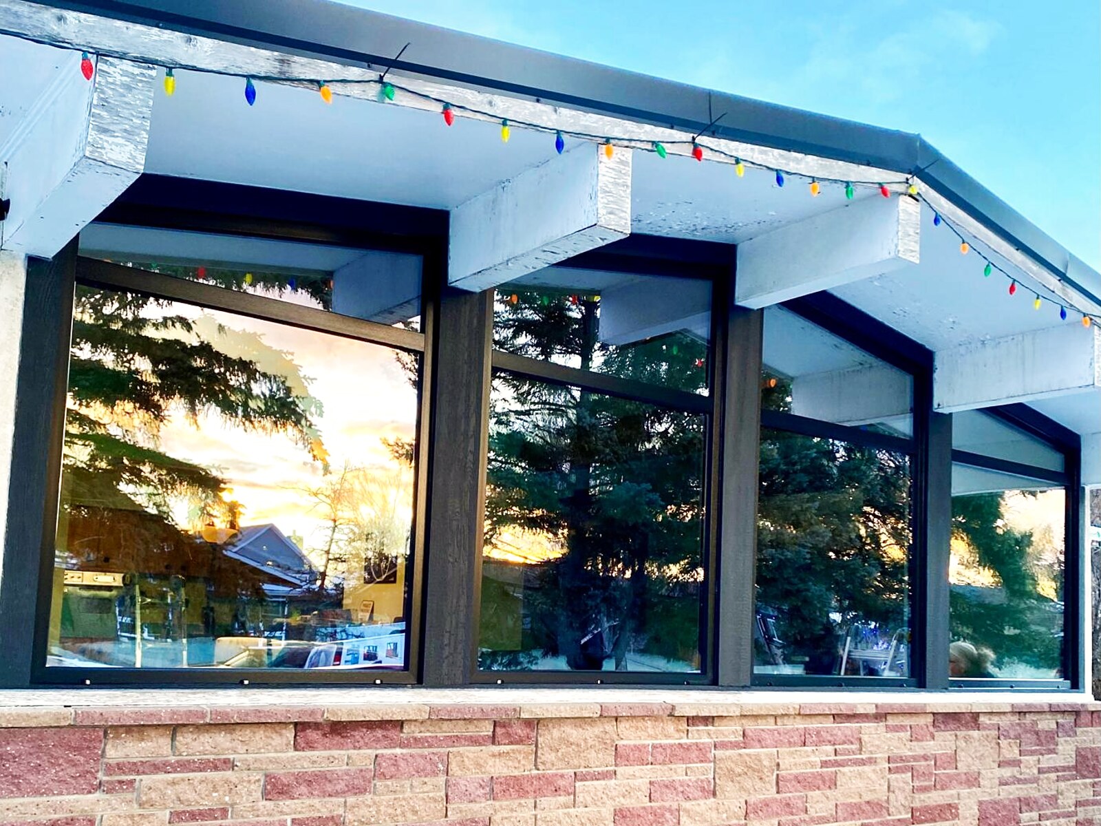 Mid-century bungalow with a continuous band of four black-frame picture windows over a rose brick base