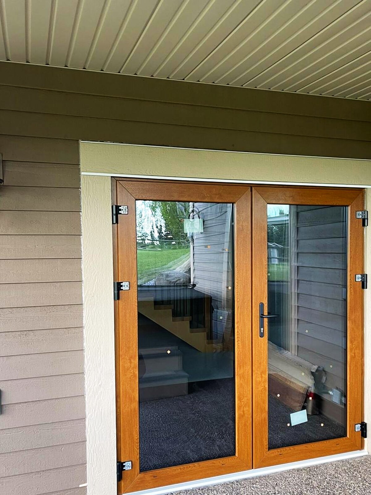 Oak-foil French double doors with full glazing under a covered entry