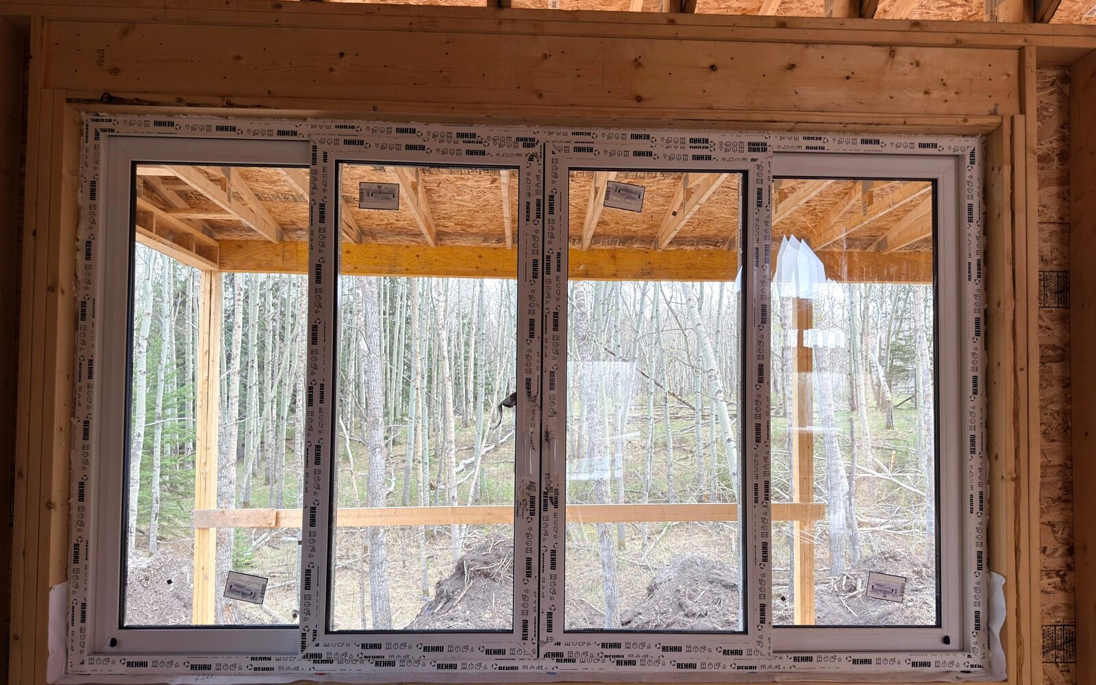Four-pane REHAU window run, glass units in factory film, installed in a framed wall