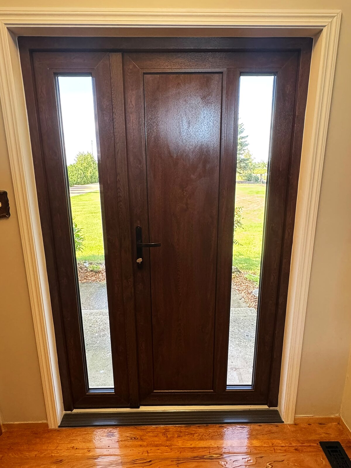 Walnut uPVC entry door with two clear sidelites, seen from the foyer