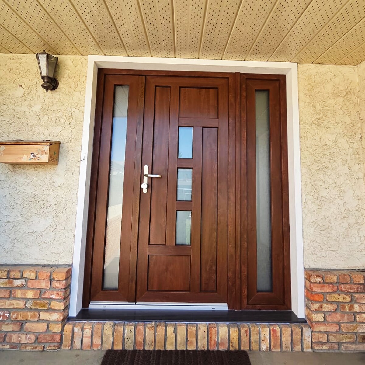 Walnut entry door with frosted sidelites, stucco and brick exterior