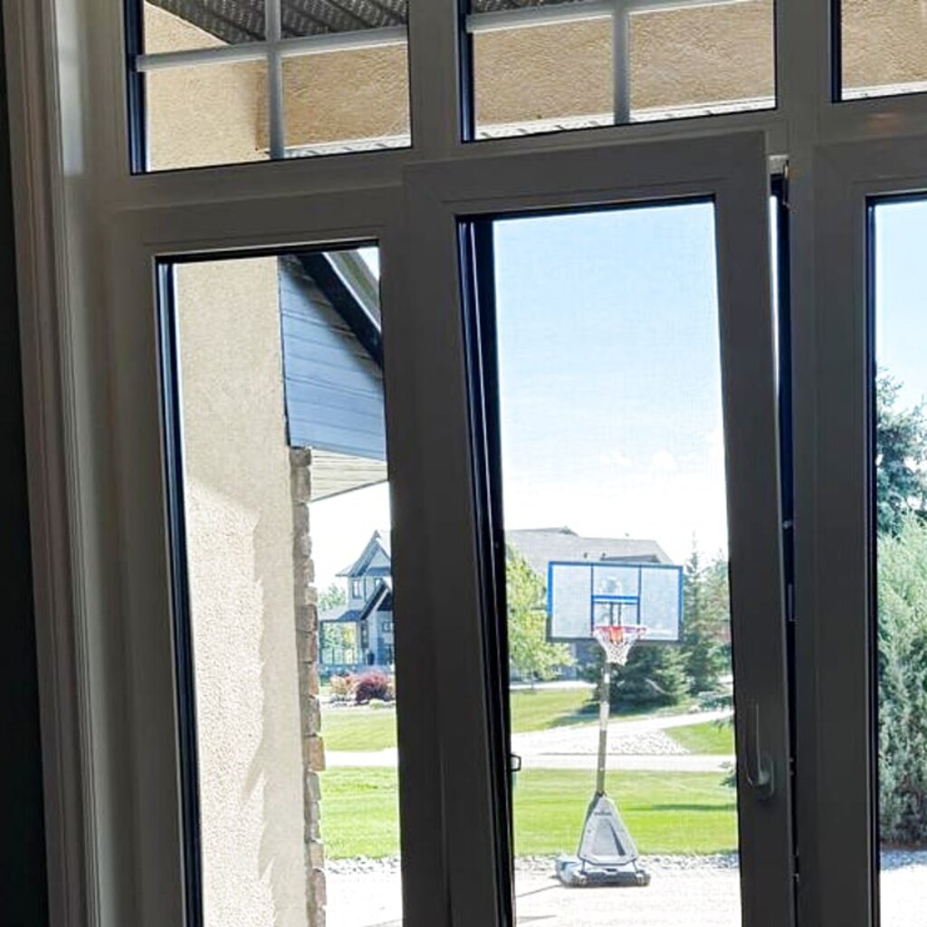 Our install: European tilt-and-turn window tilted open at the top for ventilation, white frame, Alberta home